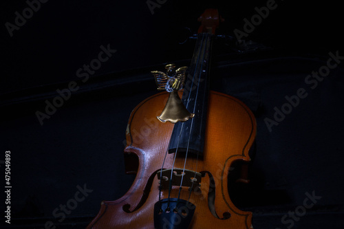 An old violin in a case and a glass toy of the Muse with a violin. Dark background. Selective focus