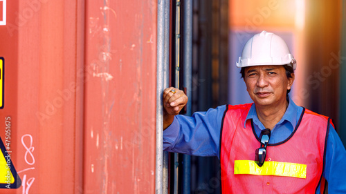 Asian male engineer standing next to container.