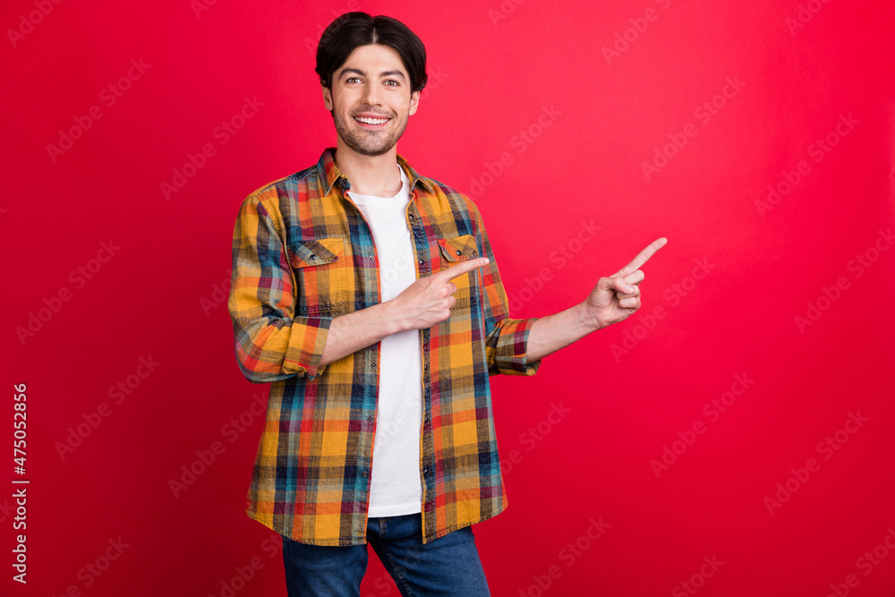 Photo of cute charming young guy dressed checkered clothes pointing fingers empty space smiling isolated red color background Photo of cute charming young guy dressed checkered clothes pointing fingers empty space smiling isolated red color background