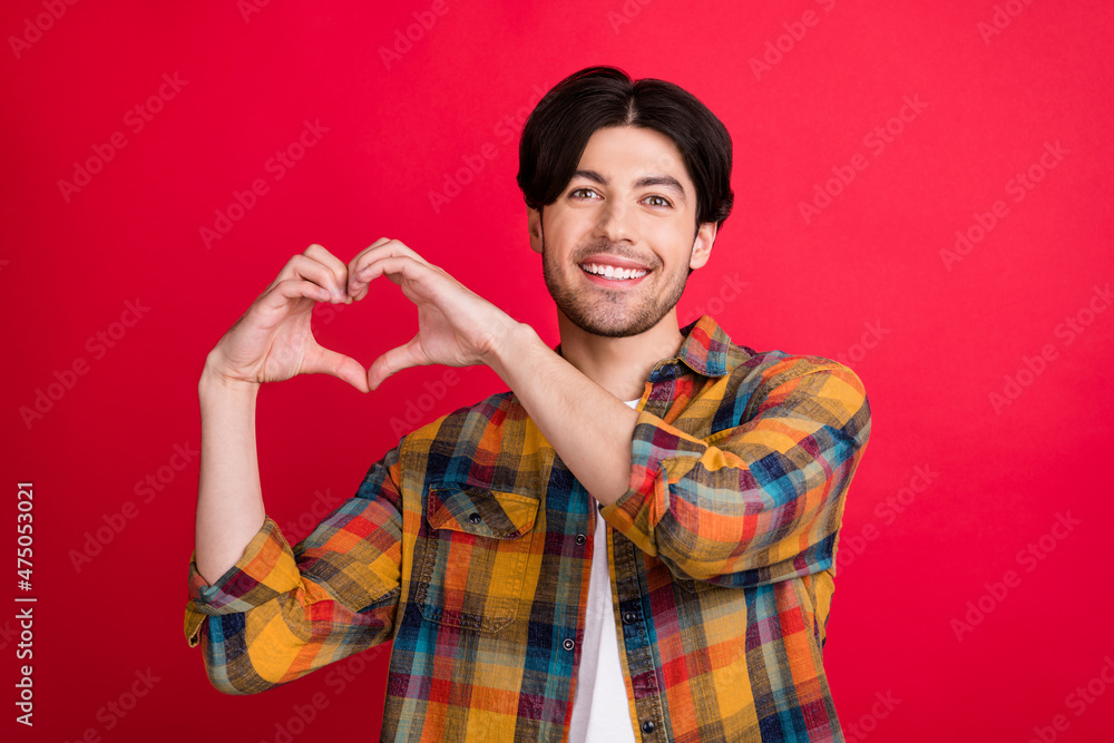 Photo of peaceful cute young guy dressed checkered clothes showing fingers heart smiling isolated red color background Photo of peaceful cute young guy dressed checkered clothes showing fingers heart smiling isolated red color background