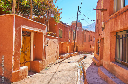 The old street of Abyaneh village with deep gutter in earthen road and preserved reddish buildings, Iran. photo