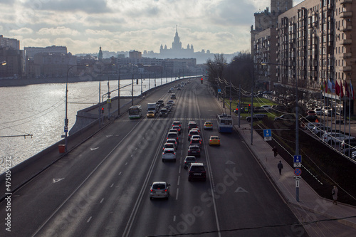 Cars stopped at a red traffic light. Car traffic at the road. Silhouette of Stalin's skyscraper. View from the Bogdan Khmelnitsky bridge. Berezhkovskaya embankment. Moscow, Russia.