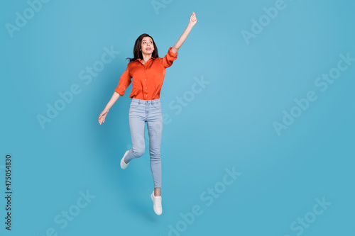 Full length body size view of attractive girl jumping holding copy space having fun isolated over bright blue color background
