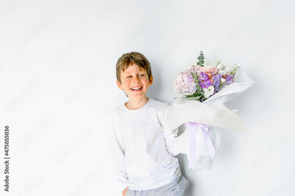 Portrait of a laughing tanned eight-year-old Caucasian boy holding a bouquet of flowers. Greeting card mockup with copy space Portrait of a laughing tanned eight-year-old Caucasian boy holding a bouquet of flowers. Greeting card mockup with copy space