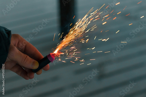 Burning Firecracker with Sparks. Guy Holding a Petard in a Hand. Loud and Dangerous New Year's Entertainment. Hooliganism with Pyrotechnics. Noise of Firecrackers in Public Places