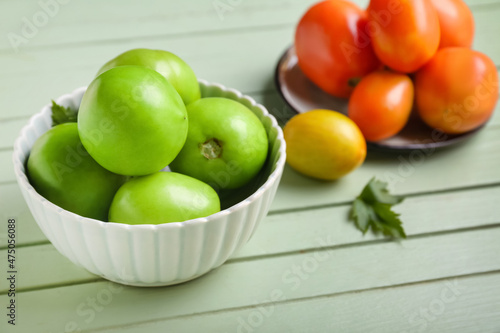 Bowls with ripe and green tomatoes on color wooden background, closeup