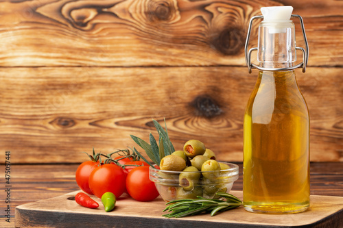 Olive oil, olives and tomatoes on wooden background