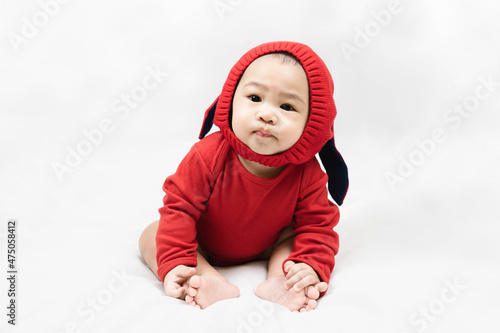 Happy infant baby boy toddler in red bodysuit and knitted hat with rabbit ears.Concept holiday Christmas, happy new year, infants, childhood.