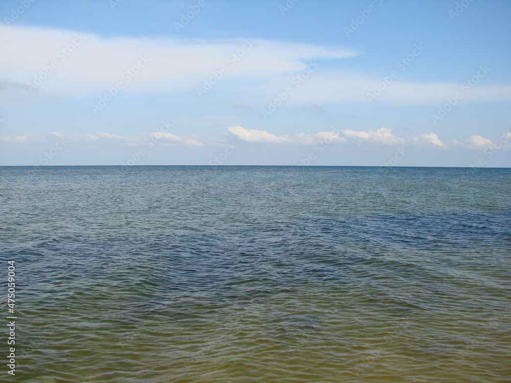 Panorama of the boundless wrinkled sea surface connecting with the blue cloudless sky on the horizon.