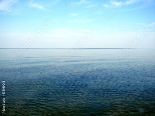 Panorama of the boundless wrinkled sea surface connecting with the blue cloudless sky on the horizon.