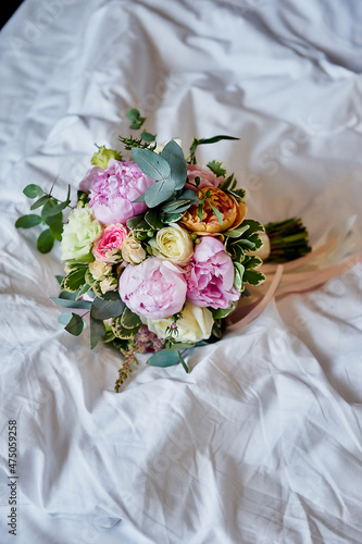 wedding bouquet with peonies lies on a white sheet