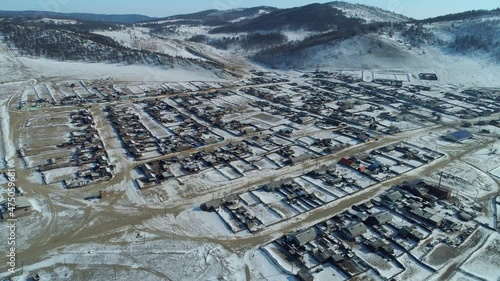 Winter snow-cowered old authentic village, wooden historic houses among mountains. Buryatia typical for Russia Siberia aerial countryside rural landscape. Baikal Territory tourist attraction. Travel photo