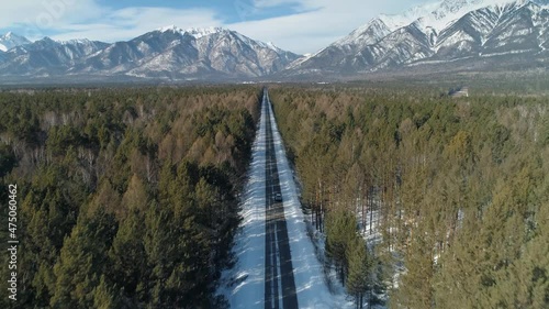 Drone forward amazing snow-capped mountains Arshan Buryatia, straight asphalt highway road to Tunki nature reserve. Winter spruce pine forest. Lonely car is driving. Adventure travel to Baikal region photo