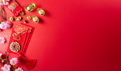 Chinese new year decorations made from red packet, orange and gold ingots or golden lump on a red background. Chinese characters FU in the article refer to fortune good luck, wealth, money flow.