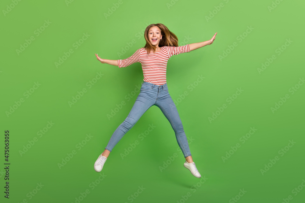 Photo of cheerful carefree lady jump enjoy weekend relax flight wear striped shirt isolated green color background Photo of cheerful carefree lady jump enjoy weekend relax flight wear striped shirt isolated green color background