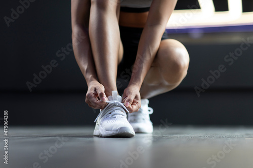 Young woman tying shoelaces at gym photo