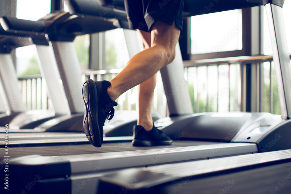 Young man running on treadmill at gym Young man running on treadmill at gym