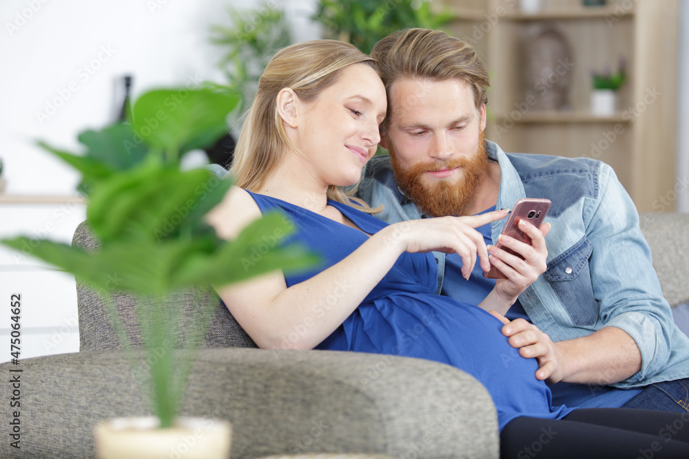 Fototapeta premium beautiful young pregnant couple using the phone