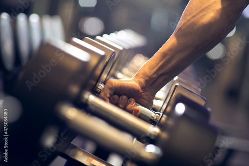 Young man working out with dumbbell at gym