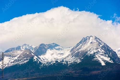 slovakia countryside landscape in spring. gorgeous High Tatra mountain ridge with snow capped peaks in the distance. grassy rural fields on a sunny day with clouds on a blue sky