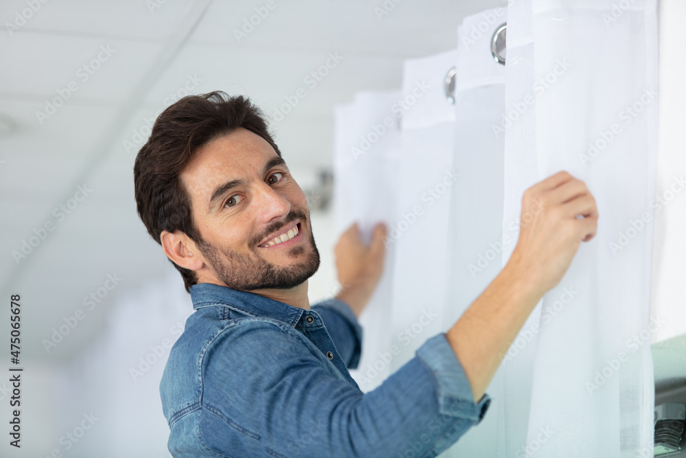 man hanging white curtains at home man hanging white curtains at home