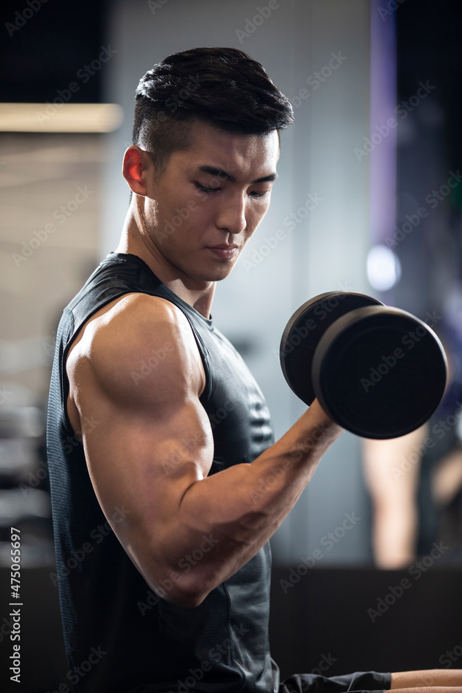 Young man working out with dumbbell at gym Young man working out with dumbbell at gym