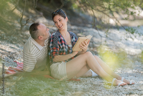 couple reading interesting book near big beautiful lake