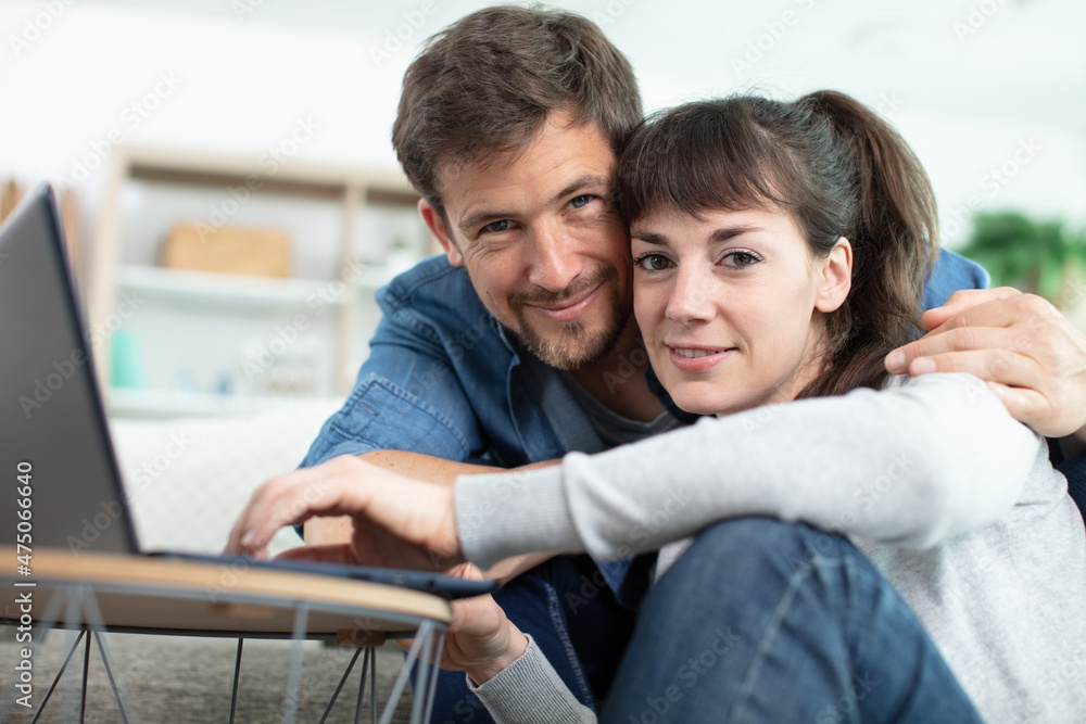 couple using laptop while sitting on floor couple using laptop while sitting on floor