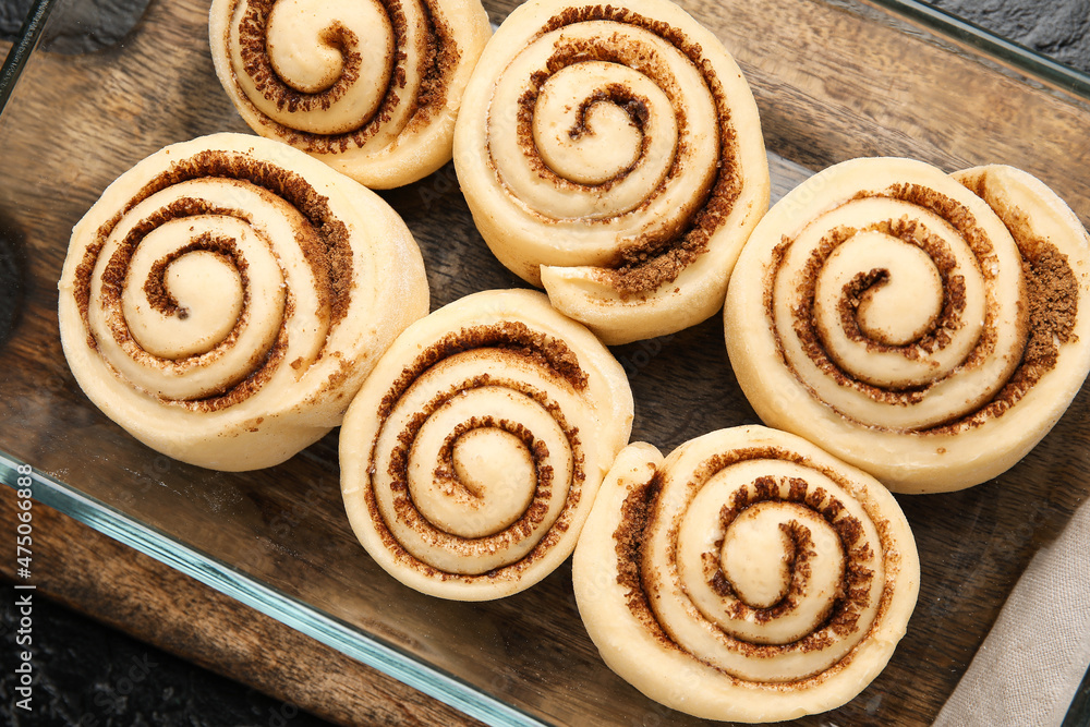 Baking dish with uncooked cinnamon rolls and on black background, closeup Baking dish with uncooked cinnamon rolls and on black background, closeup