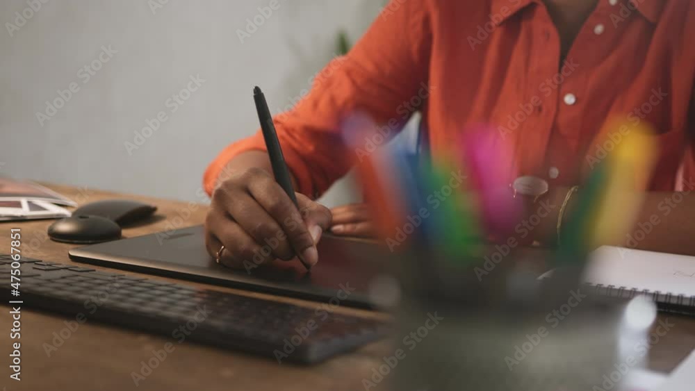 Graphic designer using a stylus pen on a digital tablet. Unrecognizable female artist drawing on a graphics tablet. Female designer working on a new project in her home office. Graphic designer using a stylus pen on a digital tablet. Unrecognizable female artist drawing on a graphics tablet. Female designer working on a new project in her home office.