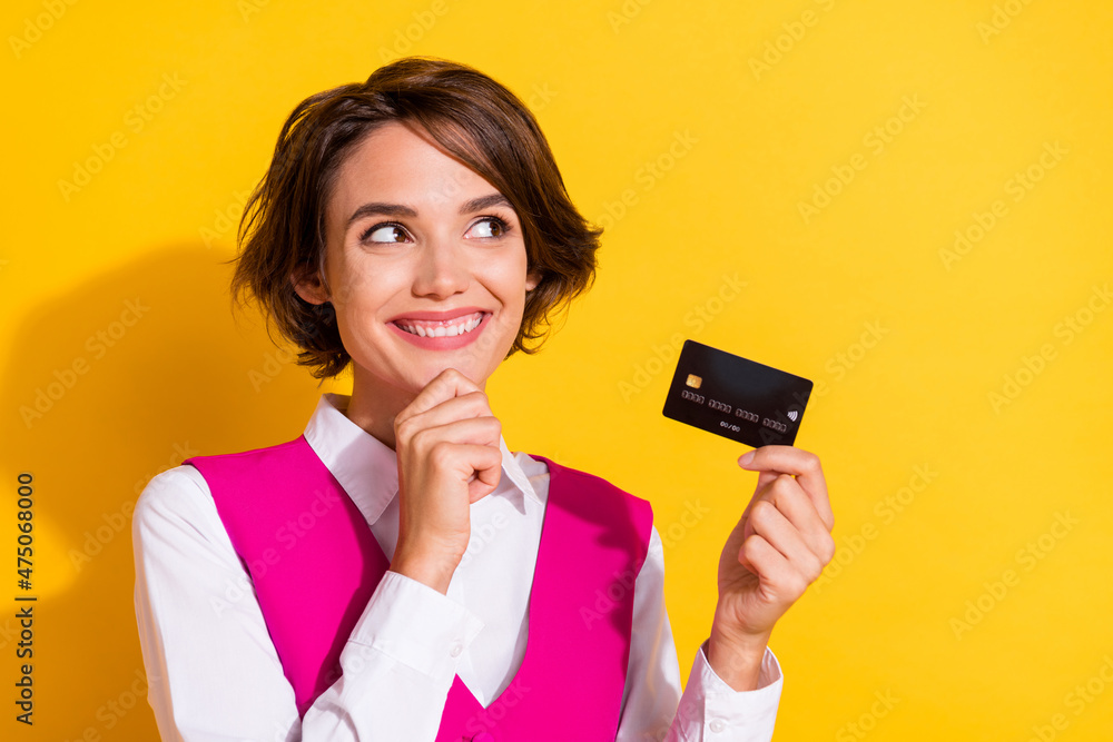 Portrait of attractive cheerful girl holding in hand bank card store cash back isolated over bright yellow color background Portrait of attractive cheerful girl holding in hand bank card store cash back isolated over bright yellow color background
