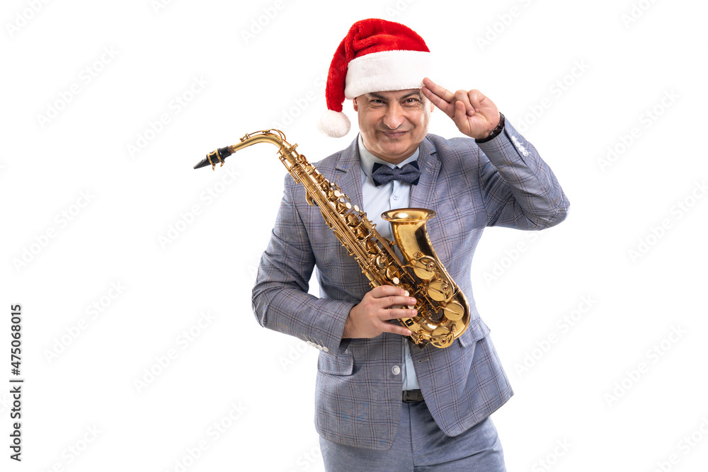 Naklejka premium Funny Musician wears in Santa's hat holds saxophone while raising hand to head on studio background