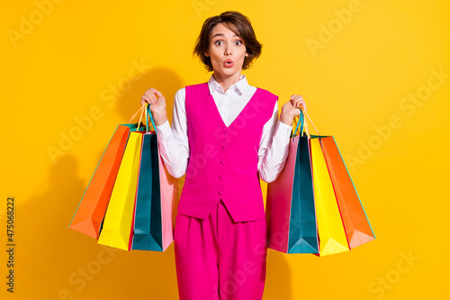 Photo of cute shocked young lady wear pink suit rising bargains big eye isolated yellow color background