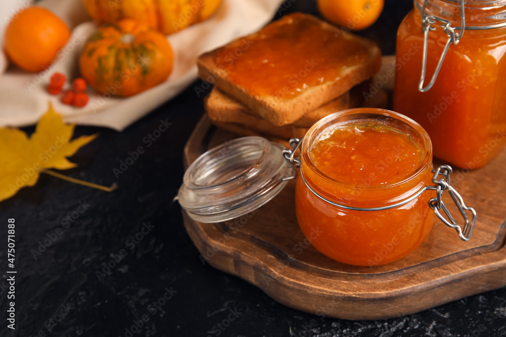 Jars of sweet pumpkin jam and toasts on black background Jars of sweet pumpkin jam and toasts on black background