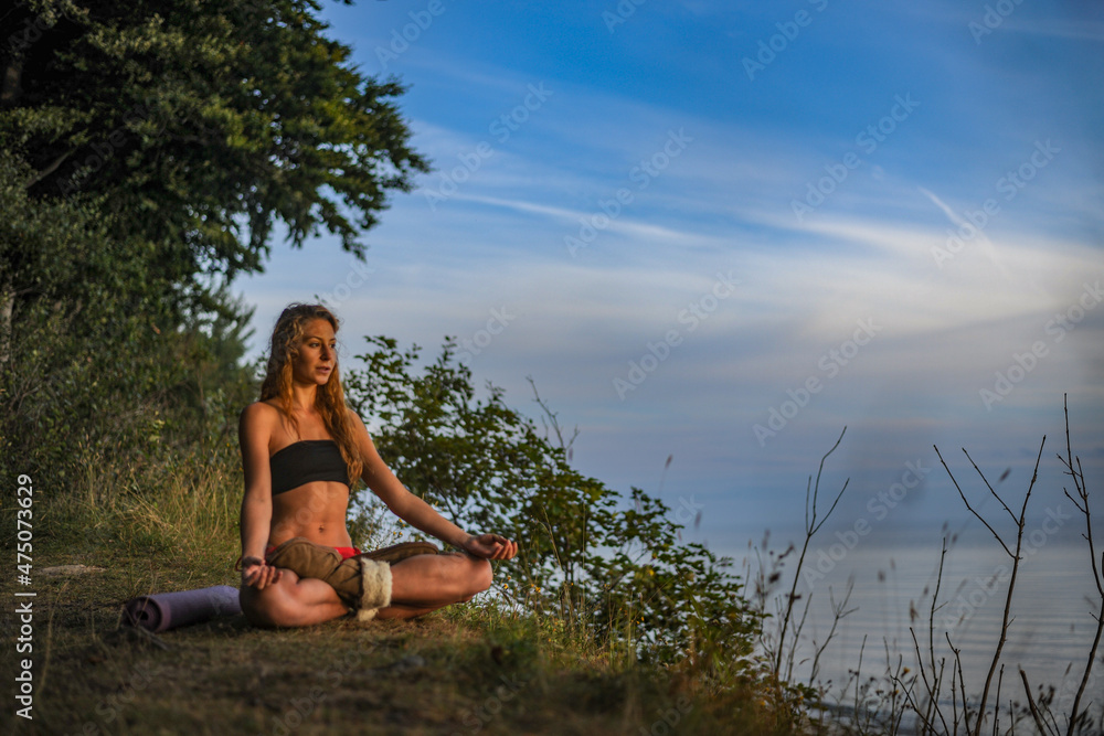 Fototapeta premium junge Frau sitzt in der Natur und meditiert im Schneidersitz