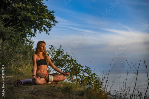 junge Frau sitzt in der Natur und meditiert im Schneidersitz