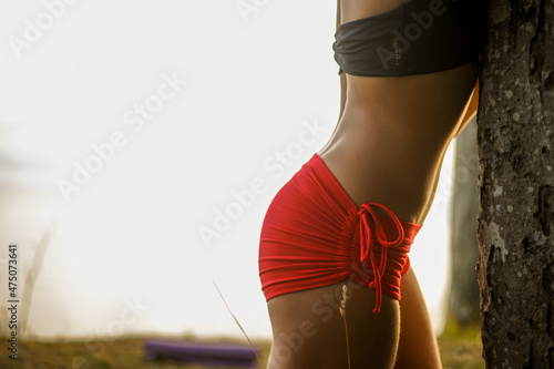 Frauenkörper im Yoga outfit an einem Baum photo