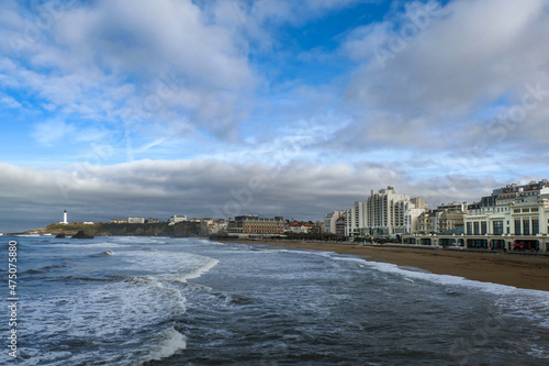 Cidade de Biarritz com a praia, um farol ao fundo à esquerda e alguns surfistas no mar photo