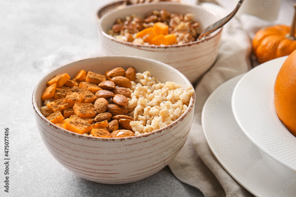 Bowls of tasty oatmeal with pumpkin and almond on light background Bowls of tasty oatmeal with pumpkin and almond on light background