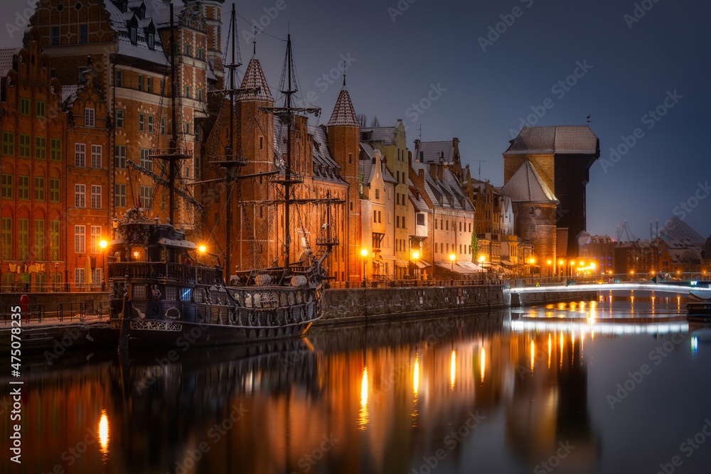 Beautiful architecture of the old town in Gdansk by the Motława river with a historic port crane at wintery night. Poland