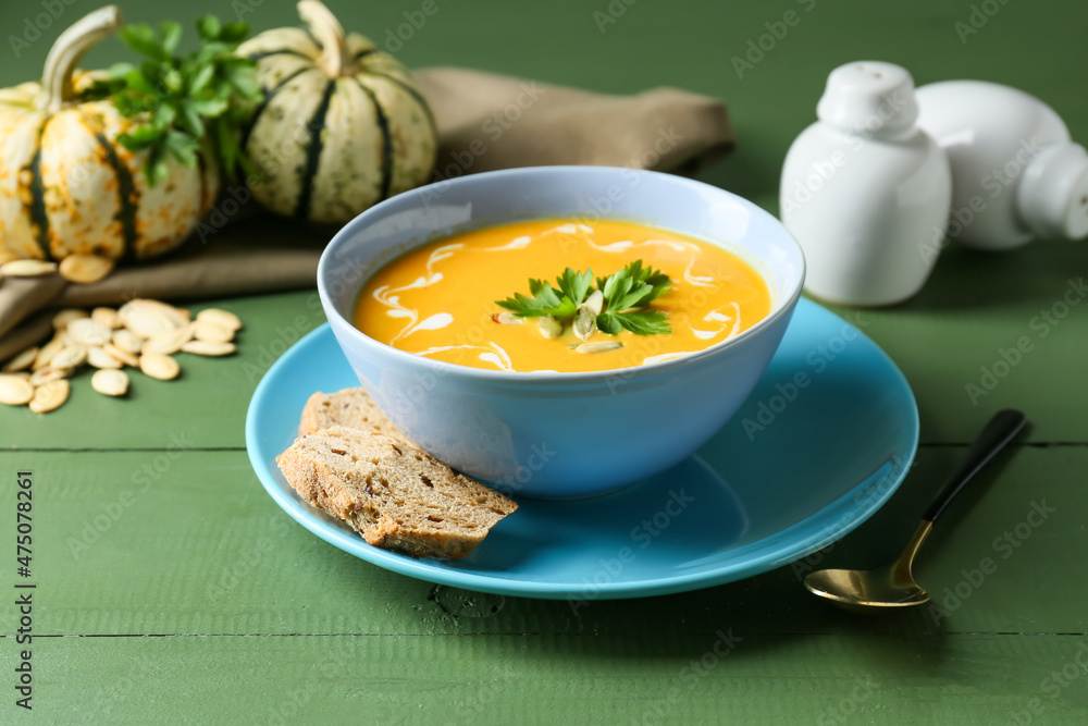 Bowl with delicious pumpkin cream soup, seeds and spices on color wooden background Bowl with delicious pumpkin cream soup, seeds and spices on color wooden background