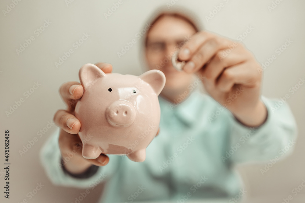 Business woman in a business shirt puts a coin in a piggy bank. Saving money for future plan and retirement fund concept.