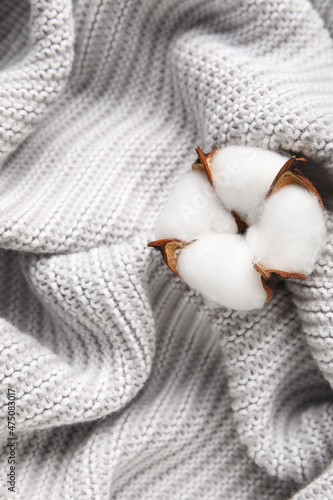 Beautiful cotton flower on light knitted fabric background, closeup © Pixel-Shot