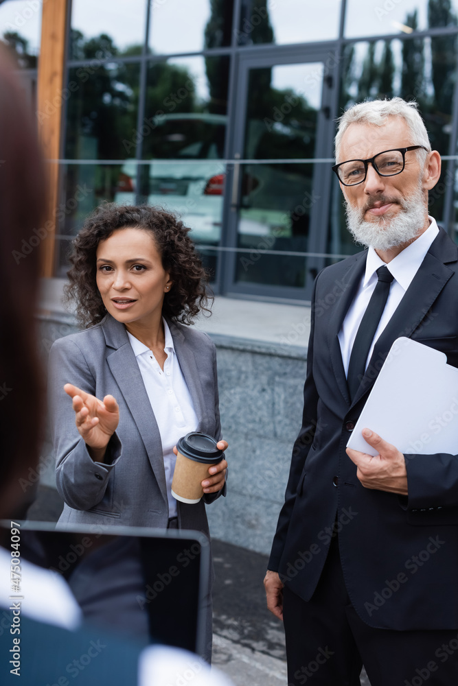 african american businesswoman pointing with hand near blurred realtor and middle aged colleague african american businesswoman pointing with hand near blurred realtor and middle aged colleague