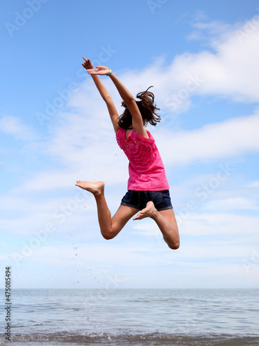 jump of a girl back to back on the seashore in the summer on the beach photo