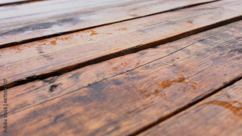 Wet brown wooden planks of wooden brown terrace. Surface of organic wood floor with many rainy puddles after heavy rain or thunderstorm. Abstract low angle view 4k stock video background Wet brown wooden planks of wooden brown terrace. Surface of organic wood floor with many rainy puddles after heavy rain or thunderstorm. Abstract low angle view 4k stock video background
