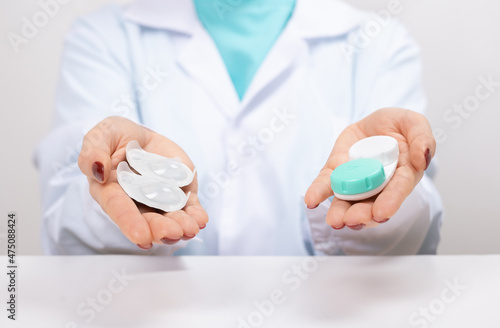 Doctor Ophthalmologist holding in hands one-day contact lenses and reusable contact lenses. choosing between types of contact lenses . myopia and eyesight problem concept