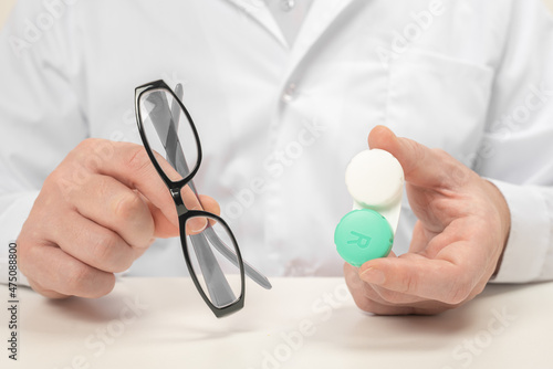 Ophthalmologist holding Eyeglasses and and Contact Lenses in hands. Choosing between contact lenses or glasses. Eyesight correction. Ophthalmology, excellent vision or optician shop concept