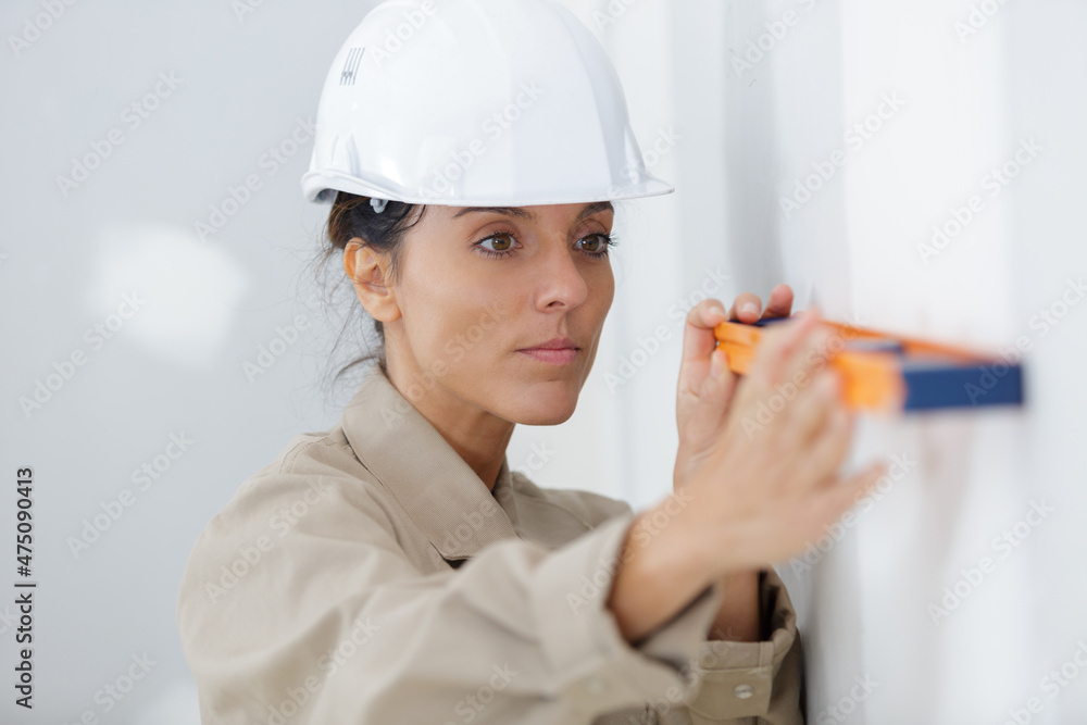 young woman builder in hardhat using spirit level young woman builder in hardhat using spirit level