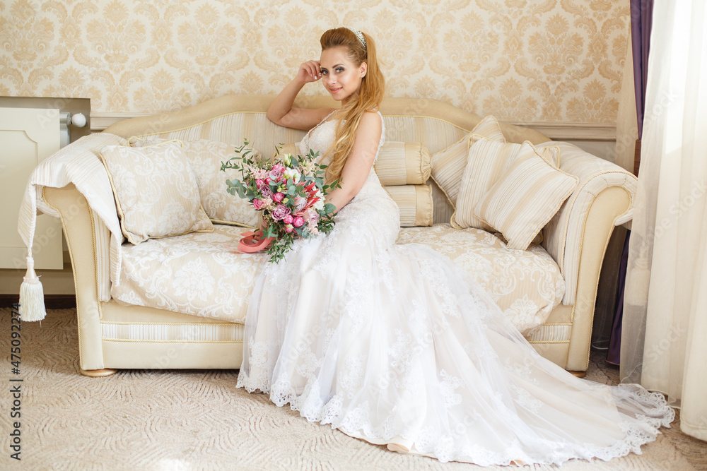 Pretty young Bride. Blonde-haired woman with wedding hair-style with a long tail. Boudoir morning of the bride. Looking to the camera or on her wedding bouquet Pretty young Bride. Blonde-haired woman with wedding hair-style with a long tail. Boudoir morning of the bride. Looking to the camera or on her wedding bouquet
